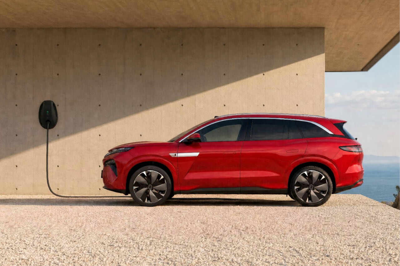 Vista lateral del nuevo SUV BYD ATTO 8 en color rojo conectado a un punto de recarga de pared