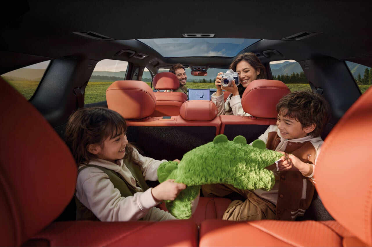 Interior espacioso del BYD ATTO 8 mostrando a una familia disfrutando en sus tres filas de asientos tapizados en piel, con un amplio techo panorámico que ilumina el habitáculo.